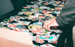 black table filled with multi-colored stickers and a hand reaching towards them