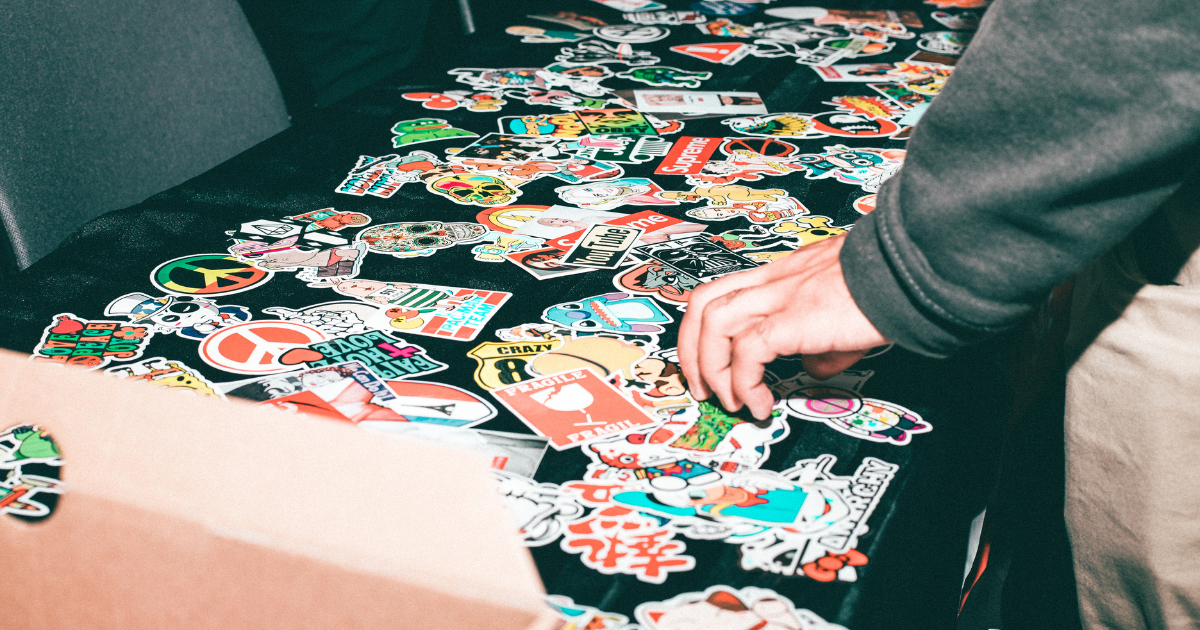 black table filled with multi-colored stickers and a hand reaching towards them